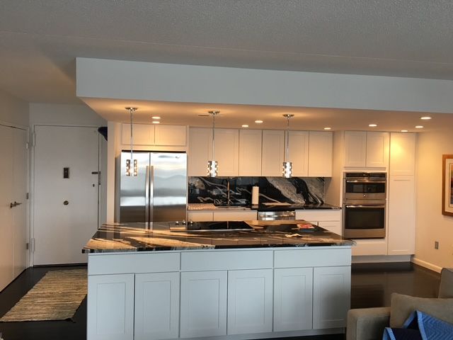 White modern kitchen with stainless steel appliances, granite countertops, and island.