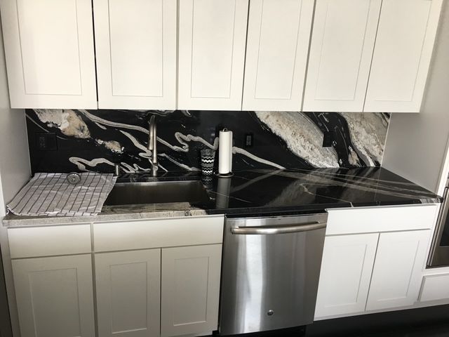 Kitchen with white cabinets, black and gold granite countertops, and stainless steel sink and dishwasher.