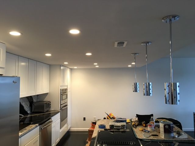 Kitchen with white cabinets, recessed lights, and pendant lights over an island.
