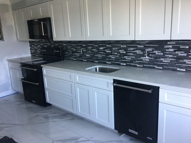 Modern kitchen with white cabinets, black appliances, and gray countertop.