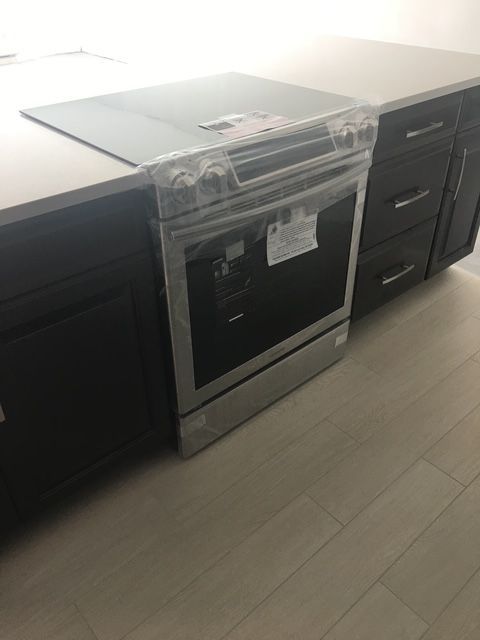 New stainless steel oven and cooktop in a kitchen with dark cabinets and light countertops.