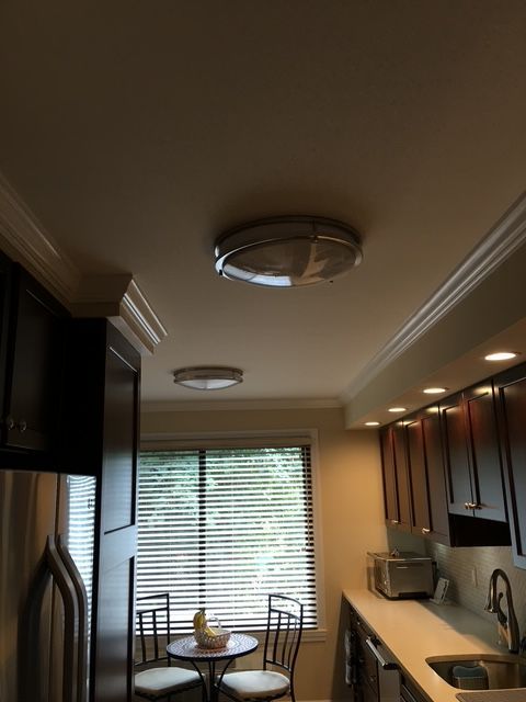 Kitchen ceiling with two round lights, cabinets, a table, and a window.