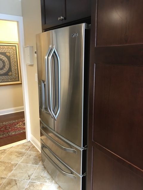 Stainless steel LG refrigerator next to a dark brown cabinet in a kitchen.