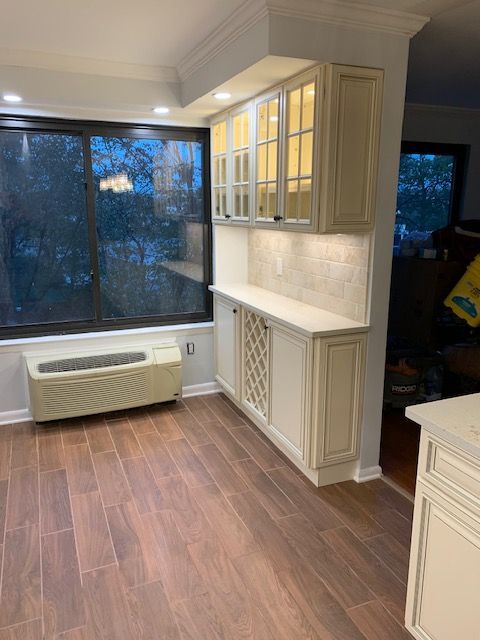 Cream-colored kitchen cabinets with a wine rack, a window, and wood-look flooring.