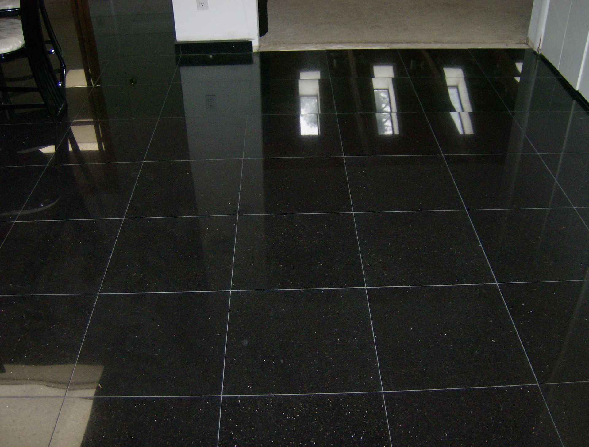 Glossy black tiled floor reflecting light from windows and doorway.