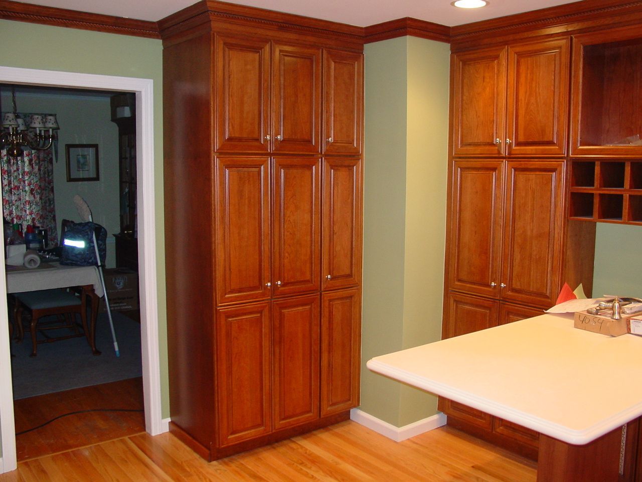 Kitchen with light wood cabinets, green walls, and a white countertop.