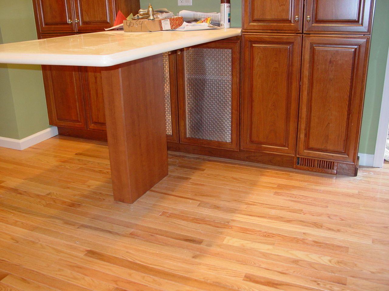 Wooden kitchen cabinets and countertop over hardwood floor.