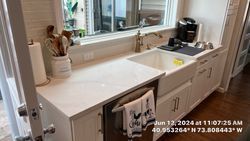 Kitchen with white cabinets, sink, and countertop, window above sink, and a coffeemaker.