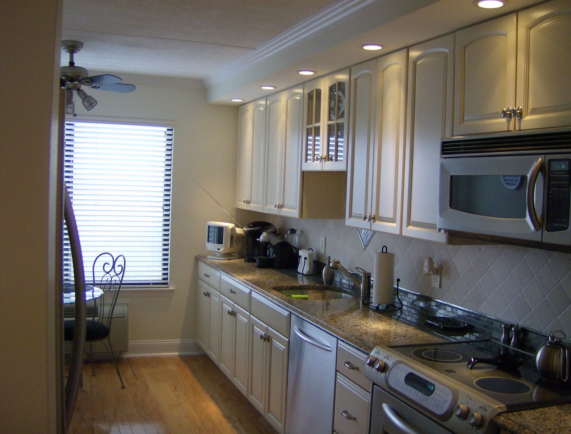 Kitchen with white cabinets, stainless steel appliances, dark countertops, and a window.