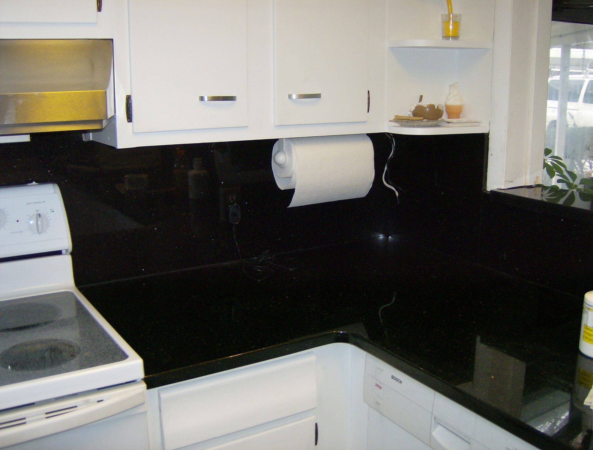 White cabinets and appliances with a black countertop in a kitchen.