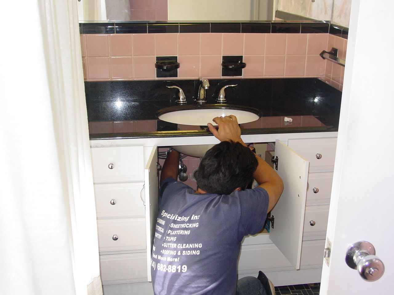 A man in overalls is standing in a kitchen with his arms crossed.