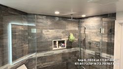Modern shower with wood-look tile, glass doors, and recessed shelves.