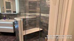 Modern bathroom with a glass shower, gray tile, and white vanity.