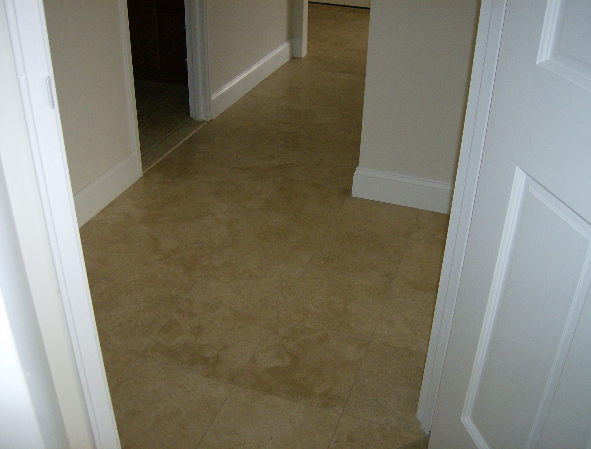 Beige hallway with tile flooring, white doors and trim.