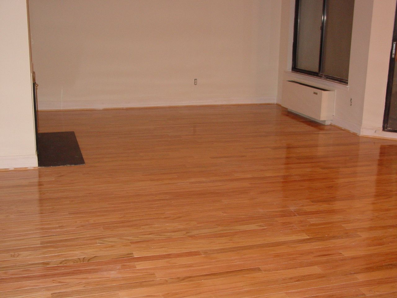 Empty room with polished wooden floors and white walls.