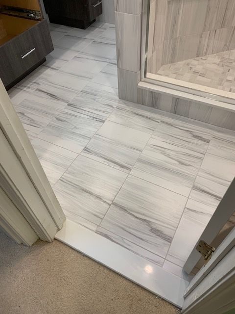White and gray marbled tile floor with a shower entry and a vanity in a bathroom.