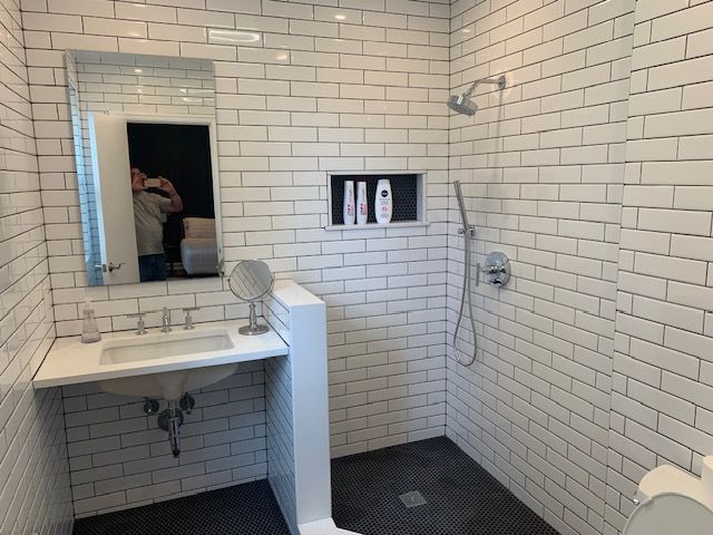 Bathroom with white subway tile, dark floor, shower, sink, and mirror.