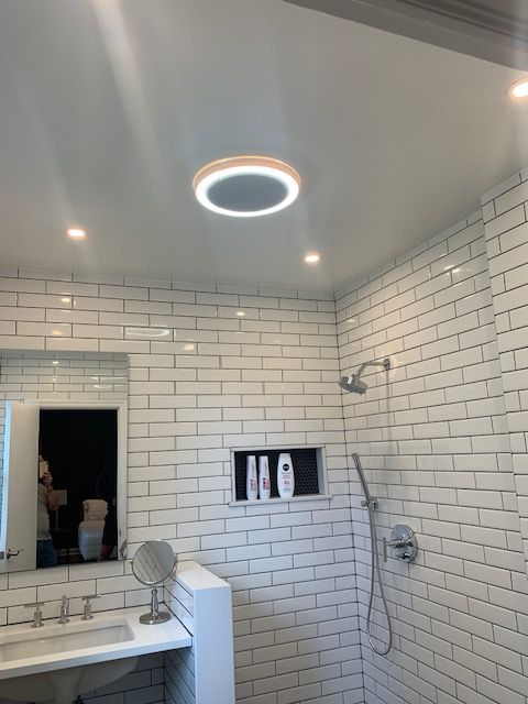 Bathroom with white subway tile, showerhead, and circular ceiling light.