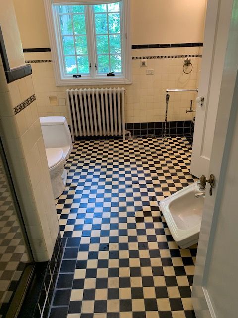 Bathroom with checkered floor, black and white tiles, toilet, bidet, radiator, and window.
