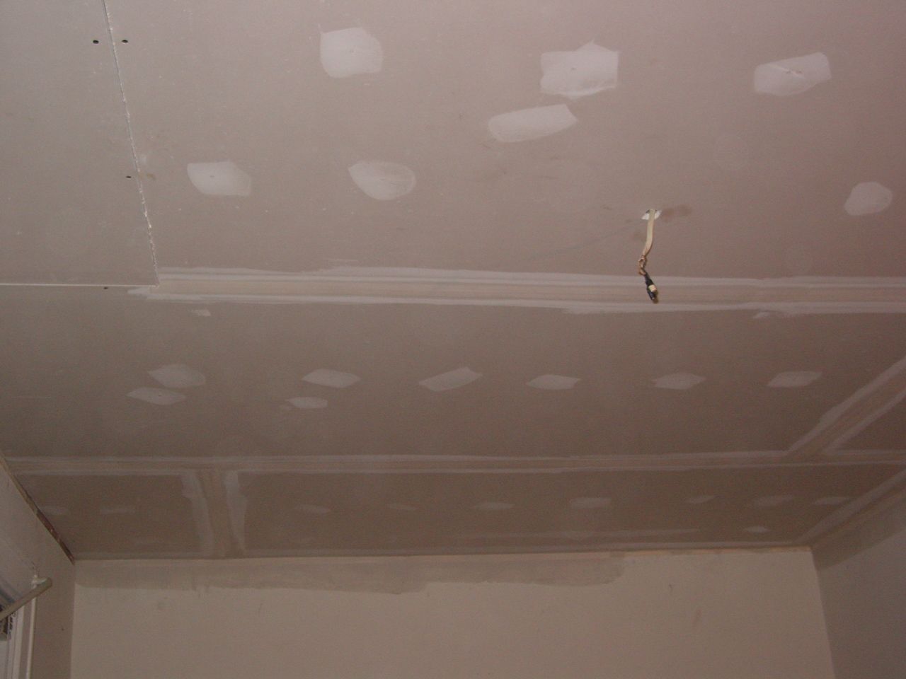 Ceiling with drywall patches, exposed wires, and partially finished plaster.