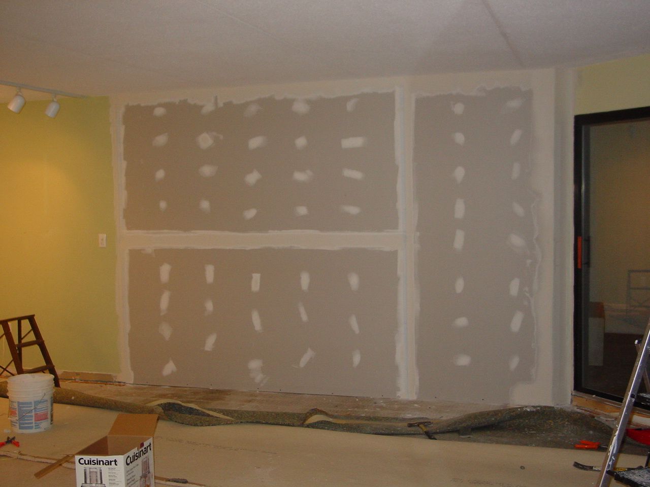 Interior wall under construction; drywall installed with mud and tape, unfinished.
