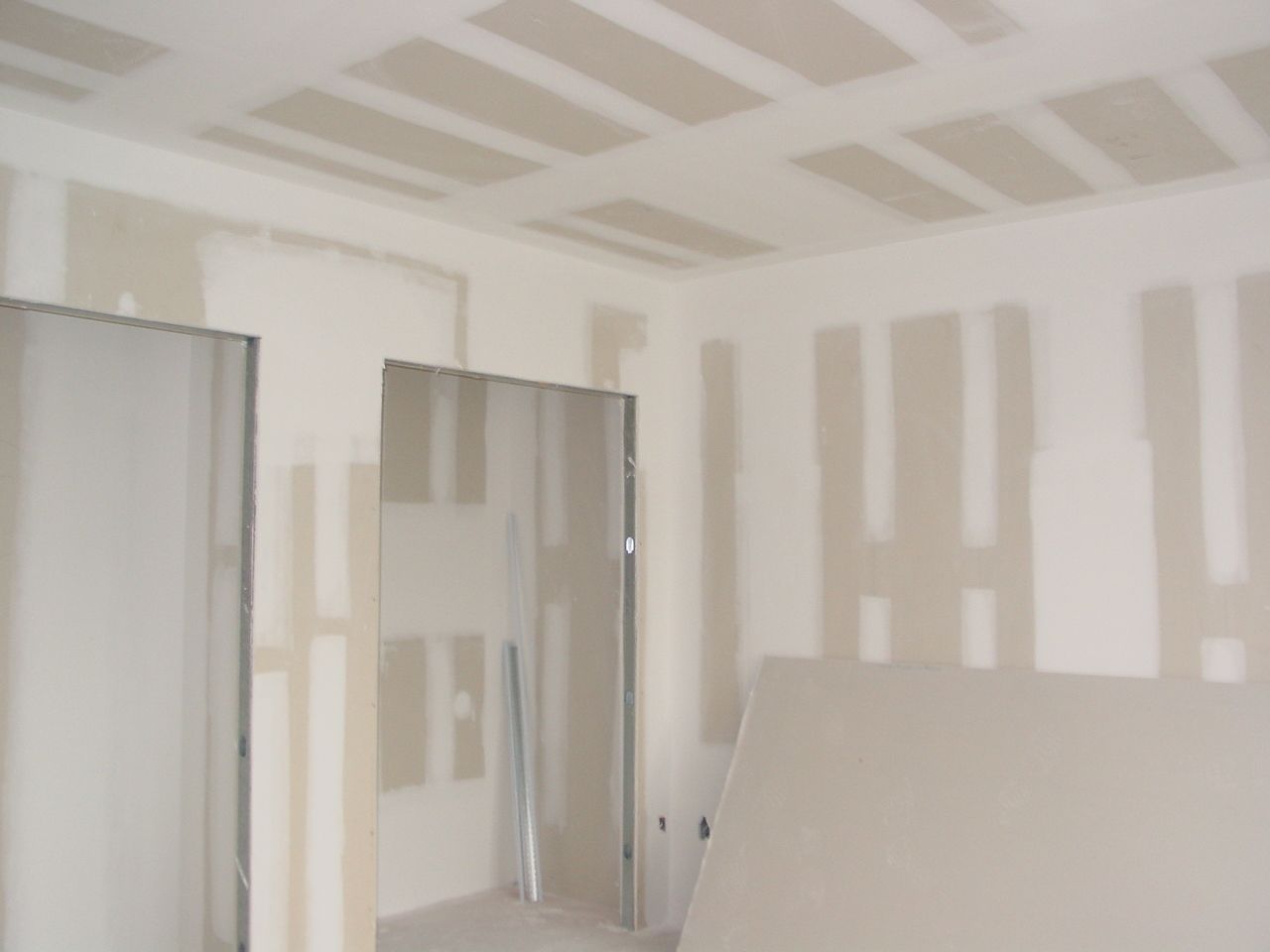 Unfinished room interior, drywall installed on walls and ceiling, metal door frames visible.