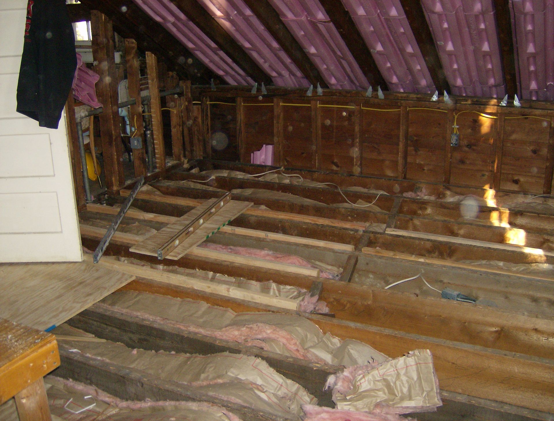 Construction site. Exposed wood beams, insulation, and partially built walls in an attic space.