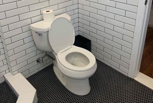 A man is installing a light fixture in a living room.