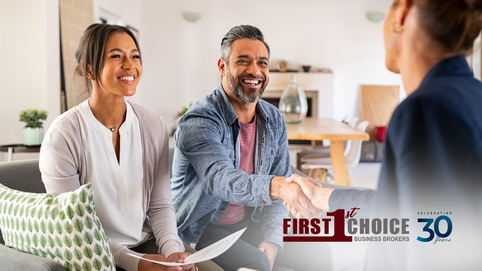 A man and woman are shaking hands with a woman while sitting on a couch.