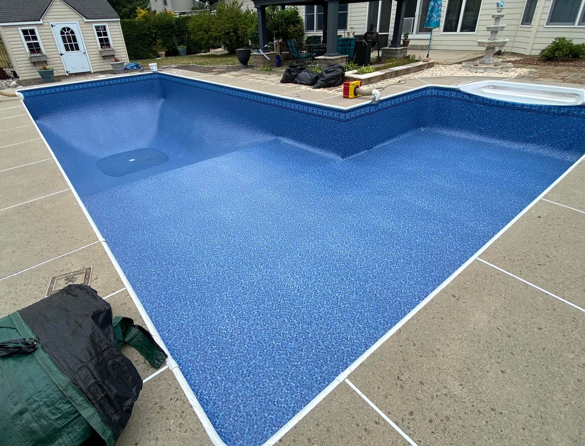 A large swimming pool is being built in the backyard of a house.