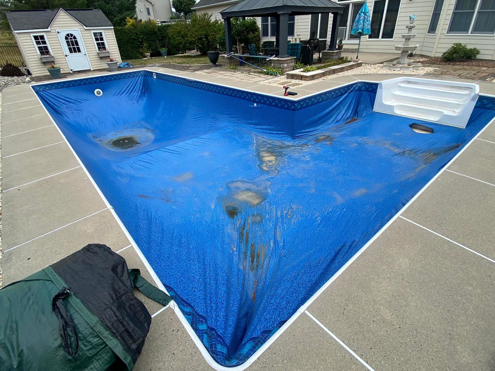 A large swimming pool is covered in a blue tarp.