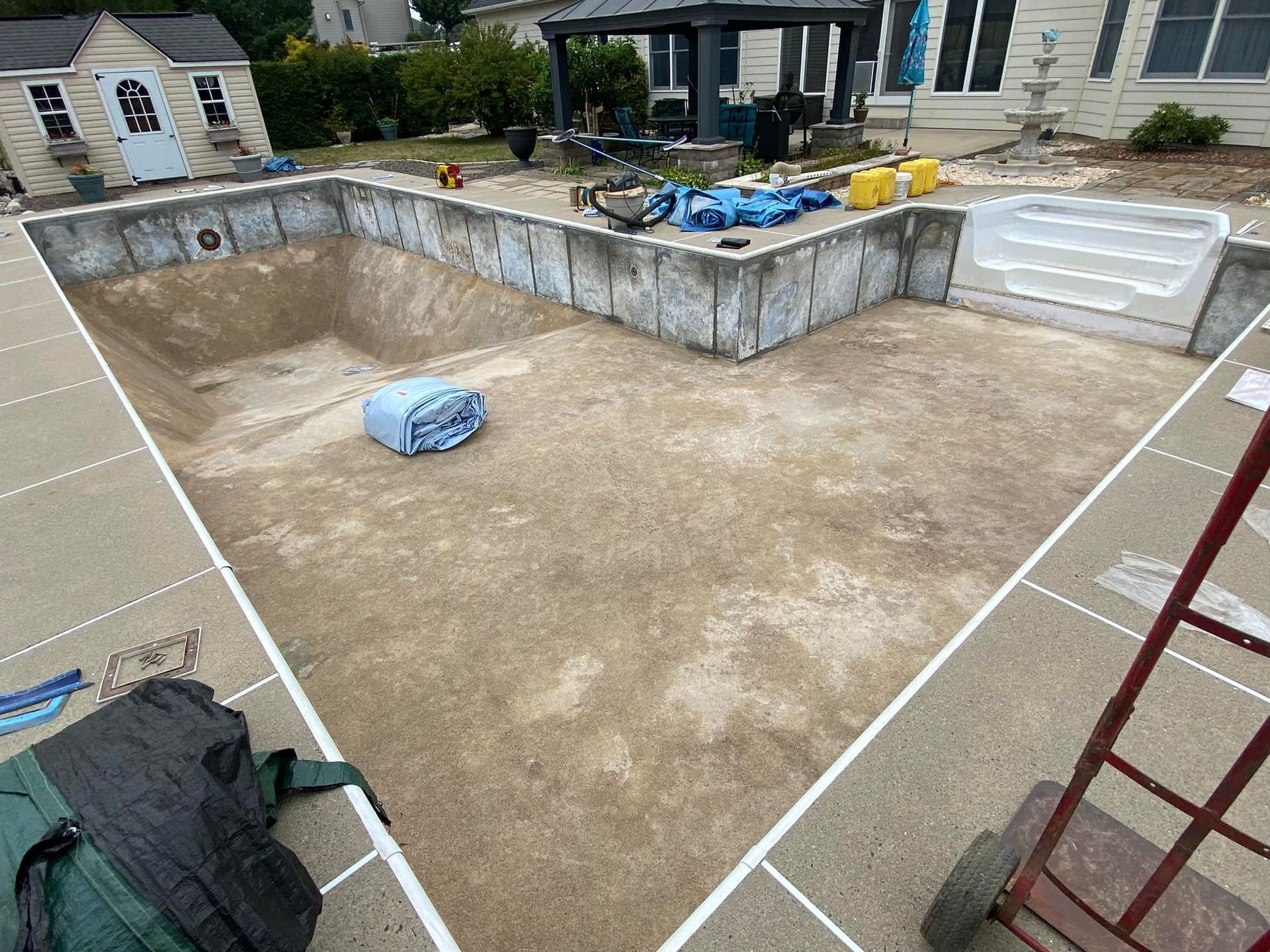 A swimming pool is being built in the backyard of a house.
