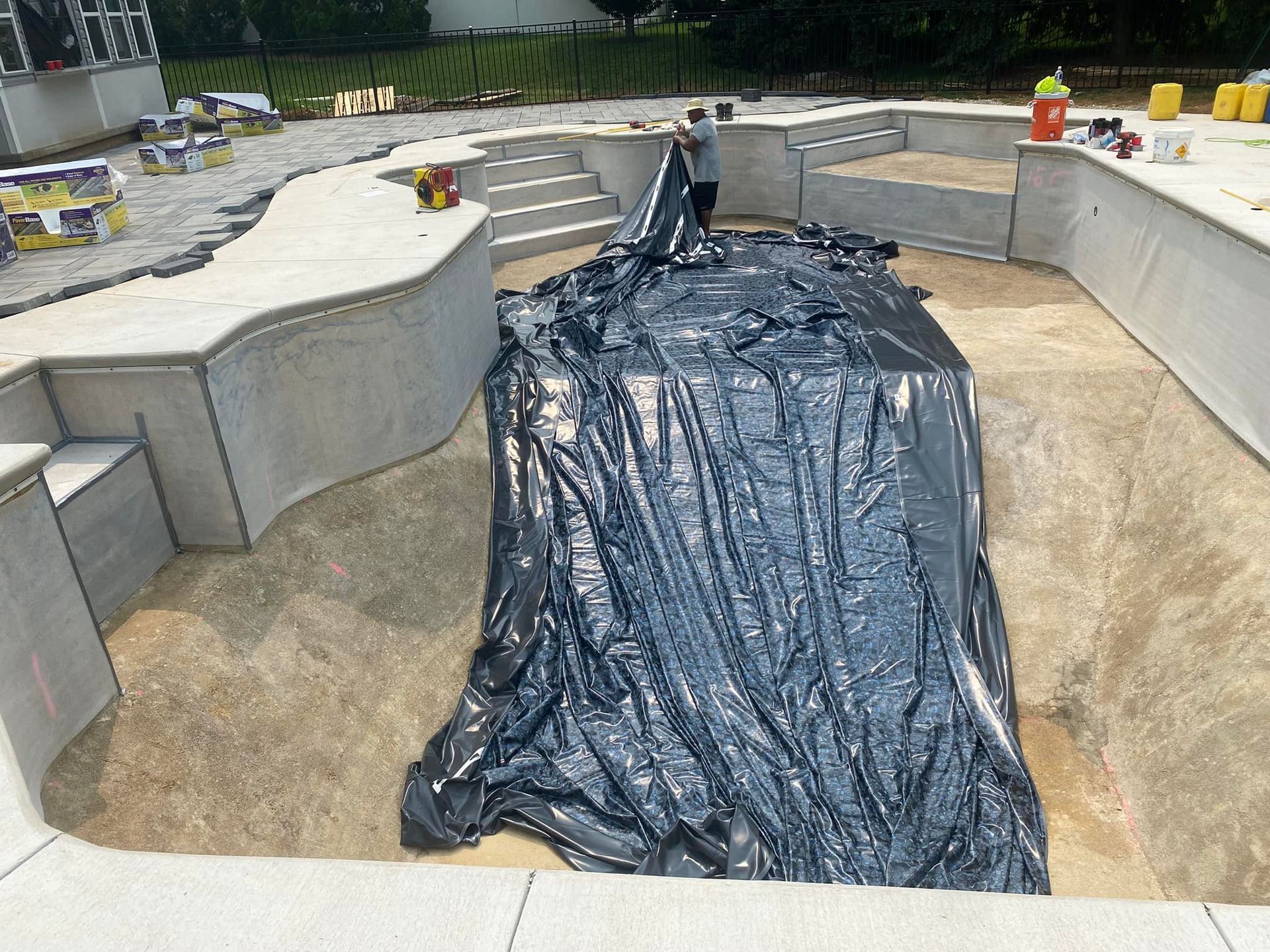 A large black tarp is covering a large hole in the ground