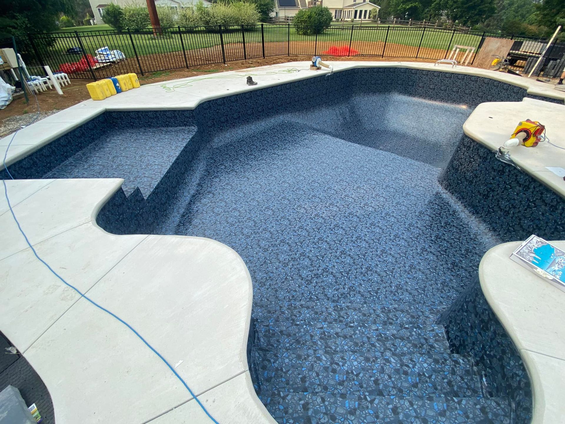 A large swimming pool is being built in a backyard.