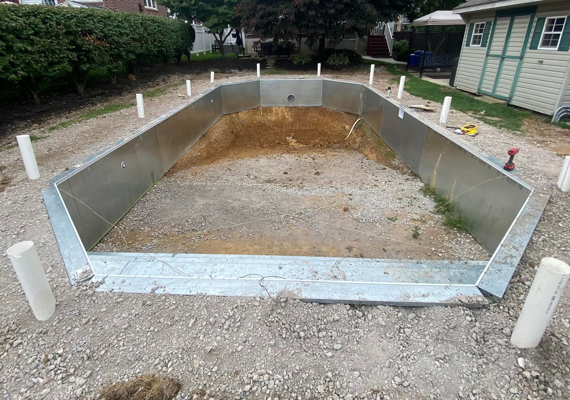 A metal swimming pool is being built in a backyard
