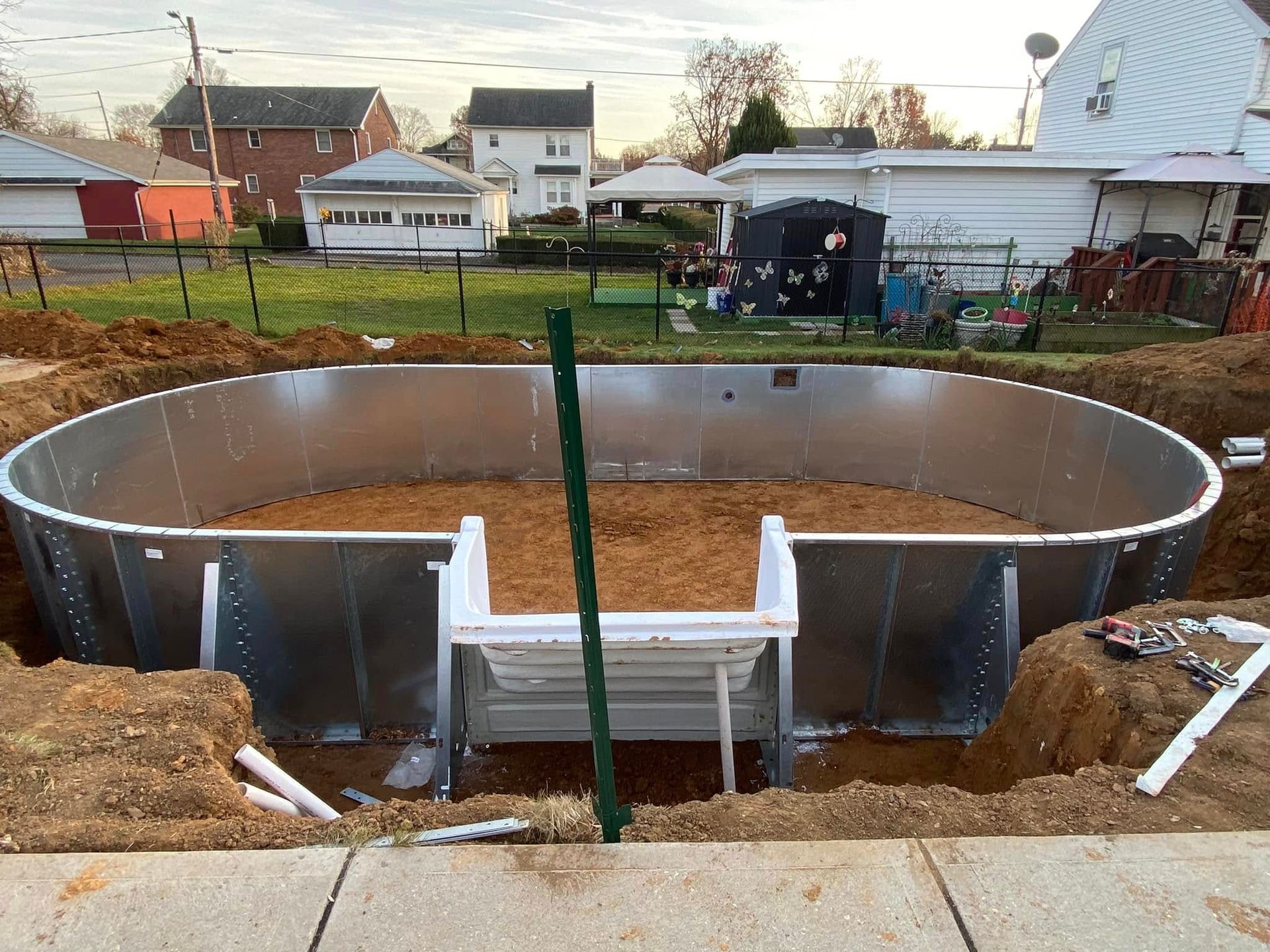 A large metal swimming pool is being built in a backyard.
