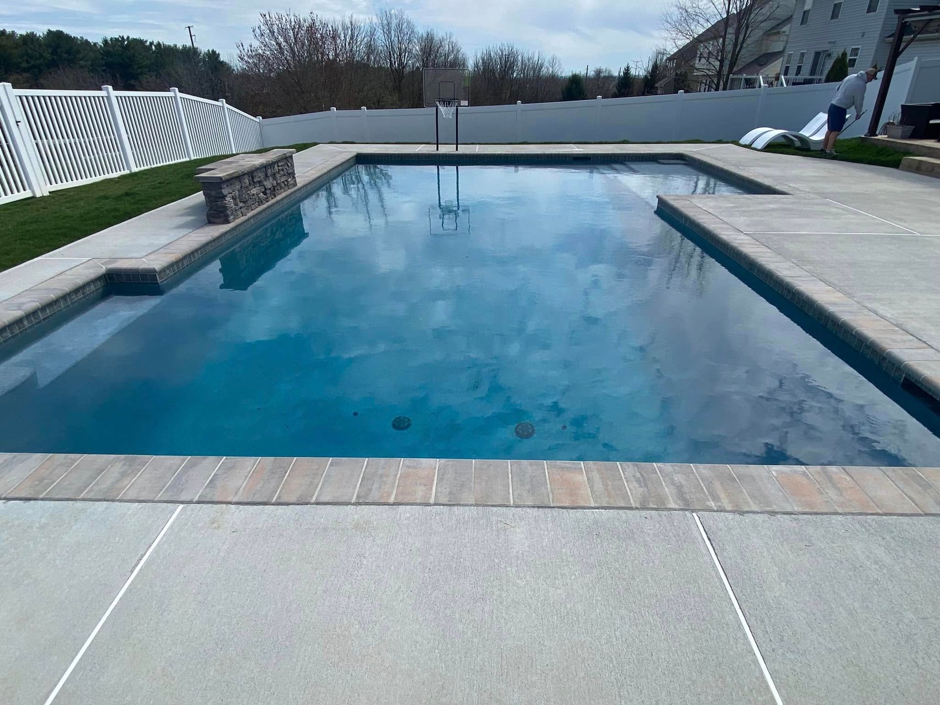 A large swimming pool with a basketball hoop in the backyard