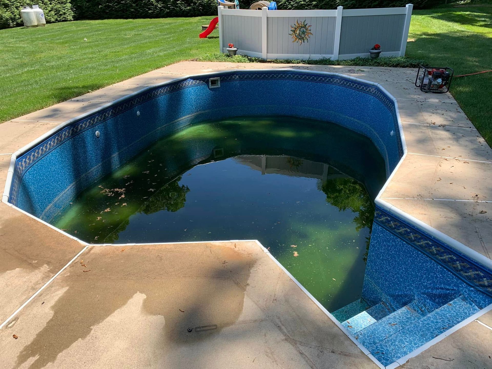 An empty swimming pool with a white fence in the background