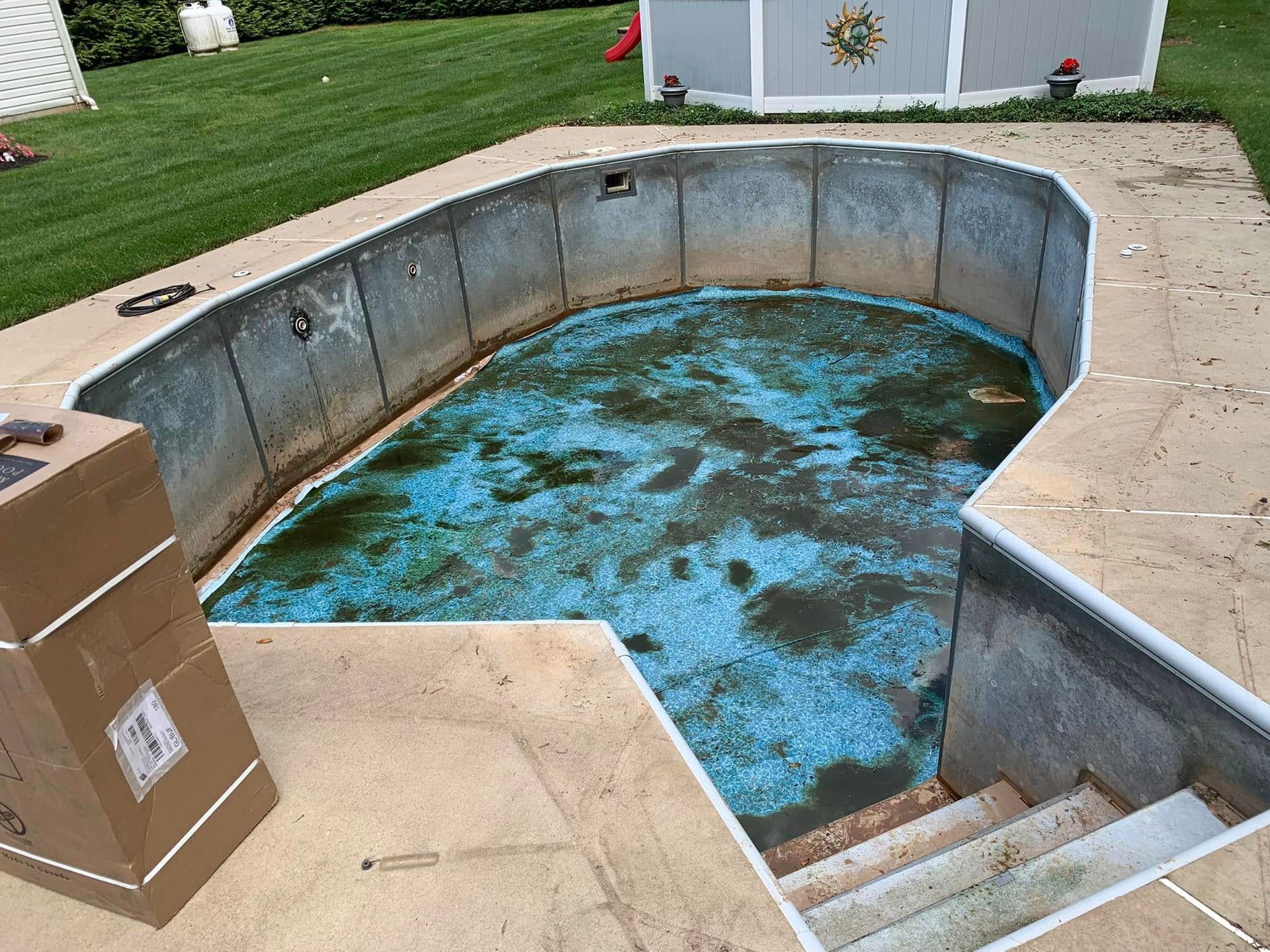 A dirty swimming pool with a box on the side of it.