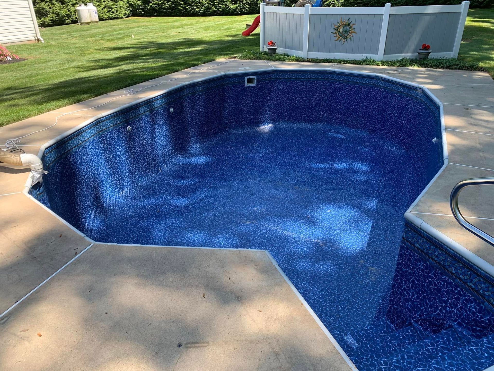 A blue swimming pool with a white fence in the background