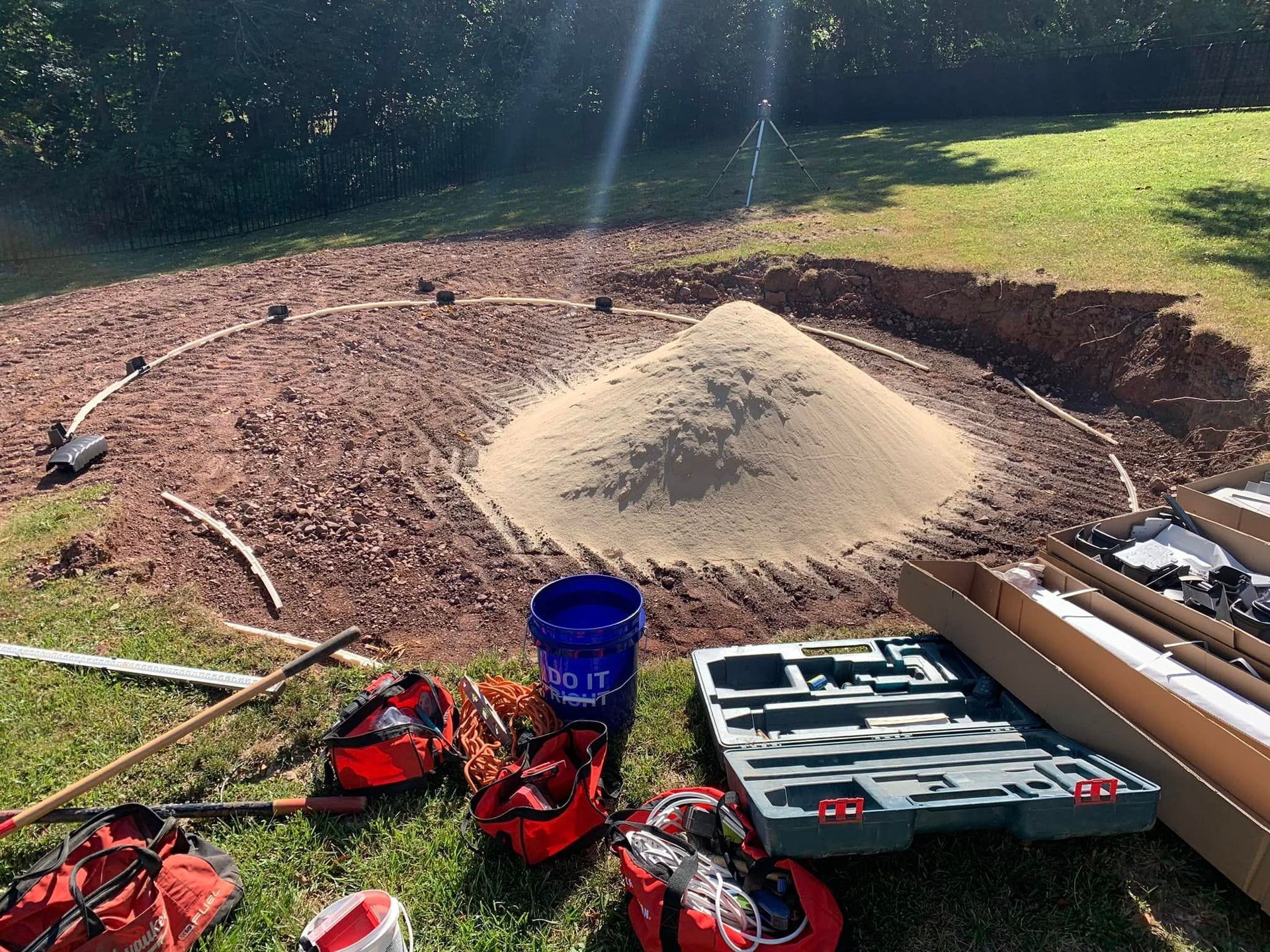 A pile of dirt is sitting on the grass next to a pile of tools.