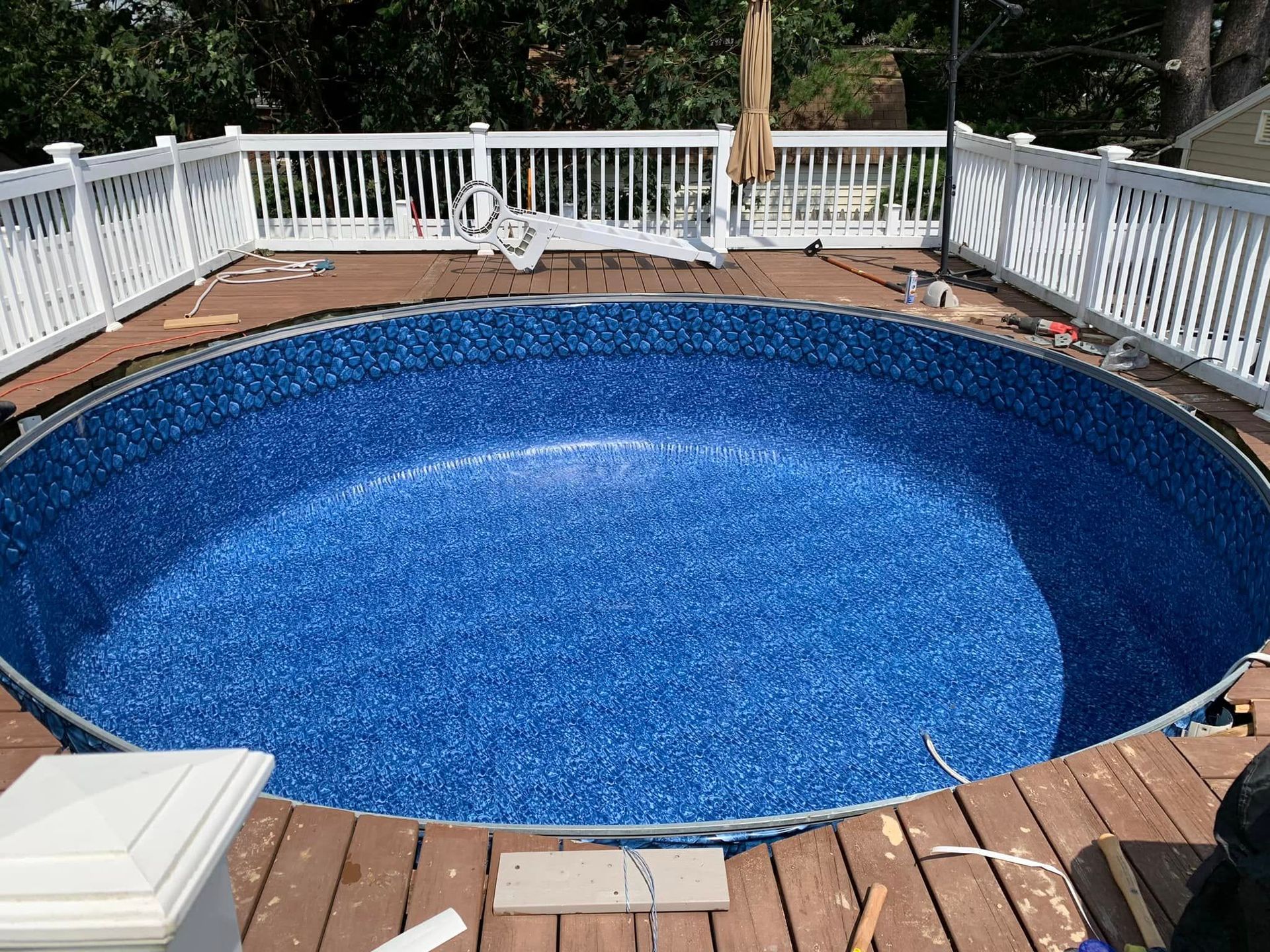 A swimming pool is being built on a deck with a white railing.