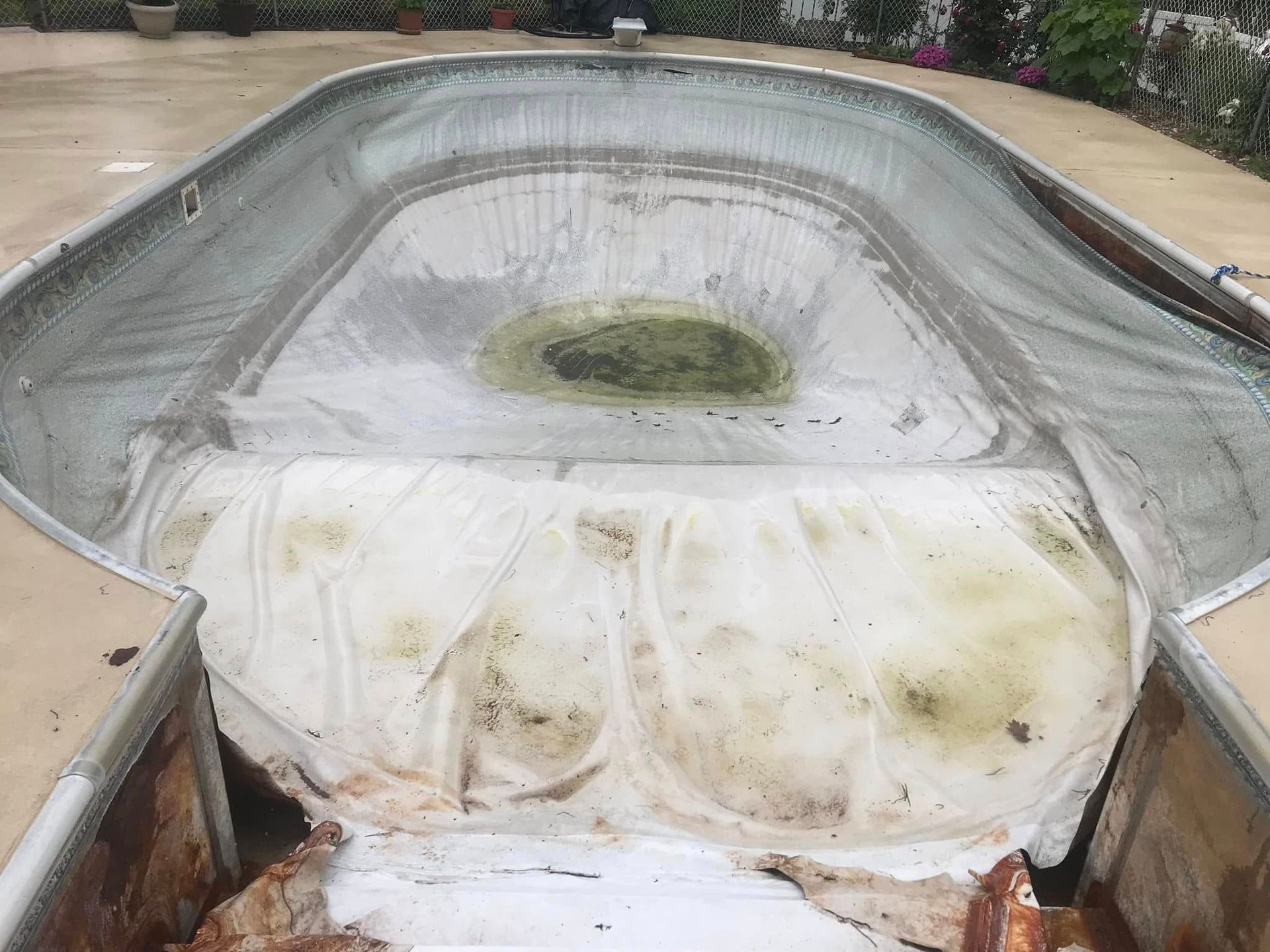 An empty swimming pool with a white tarp on top of it.