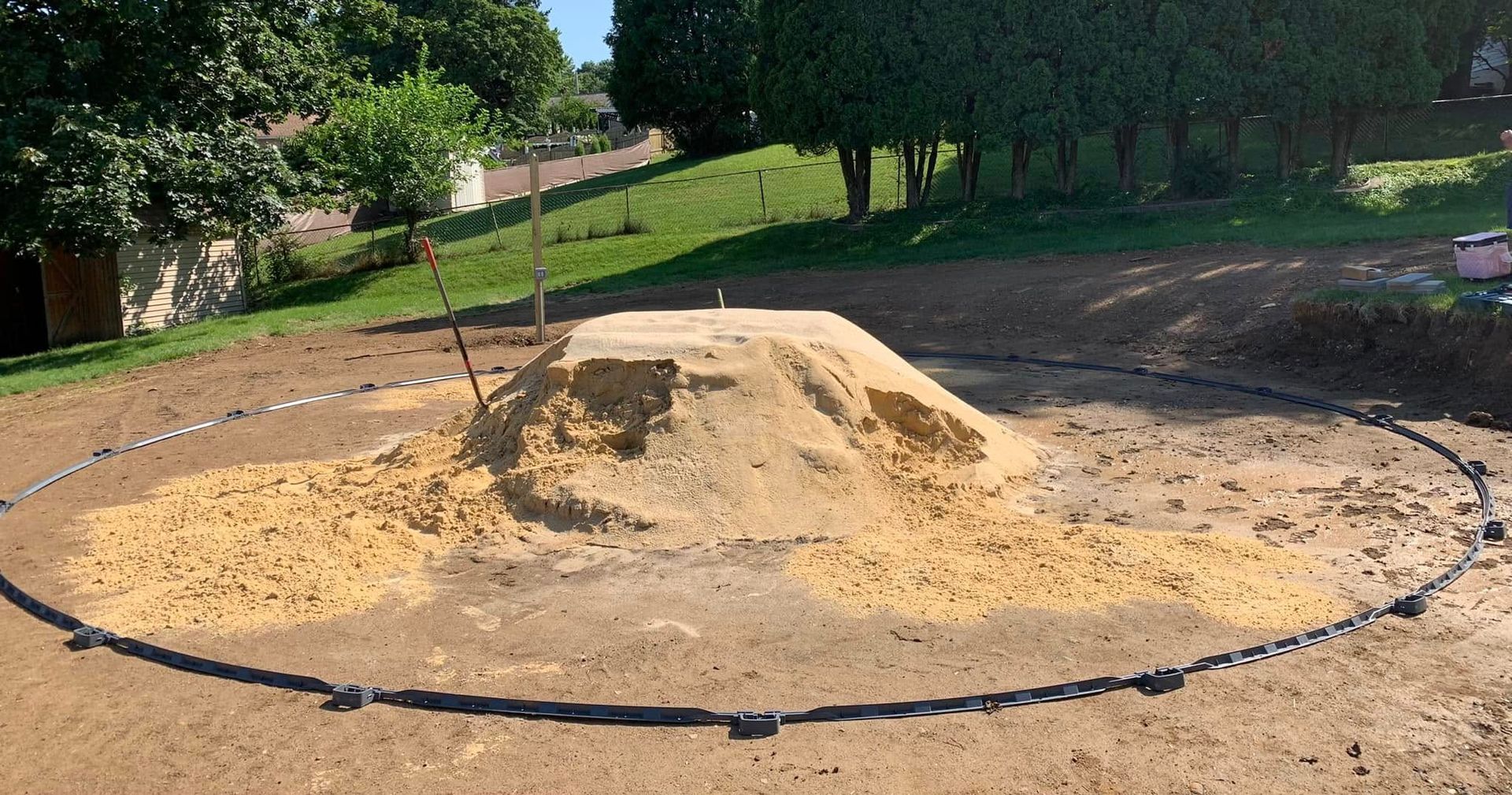 A pile of sand is sitting in the middle of a dirt field.
