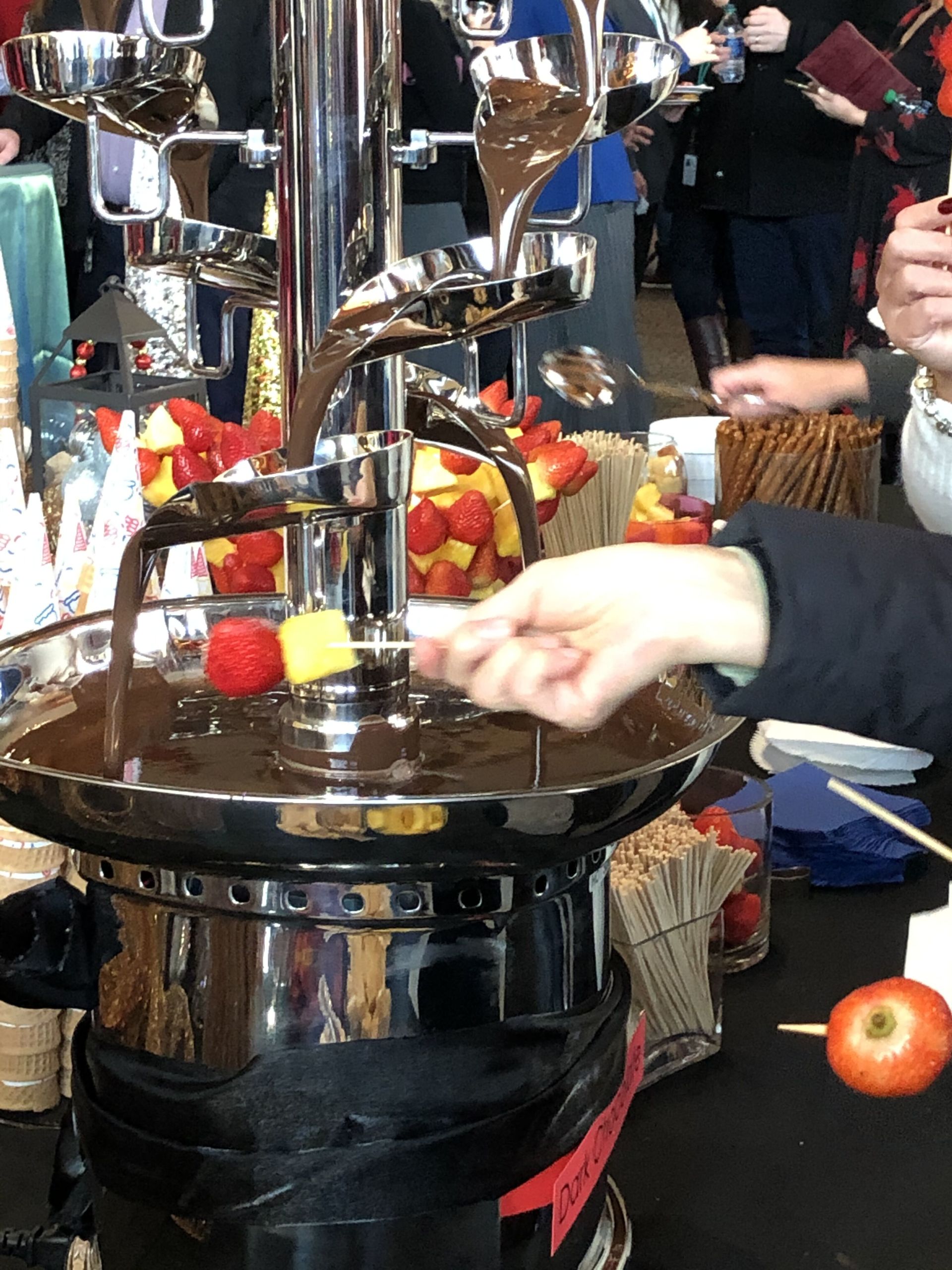A person is pouring chocolate into a bowl of fruit