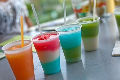 A row of colorful drinks with straws on a table