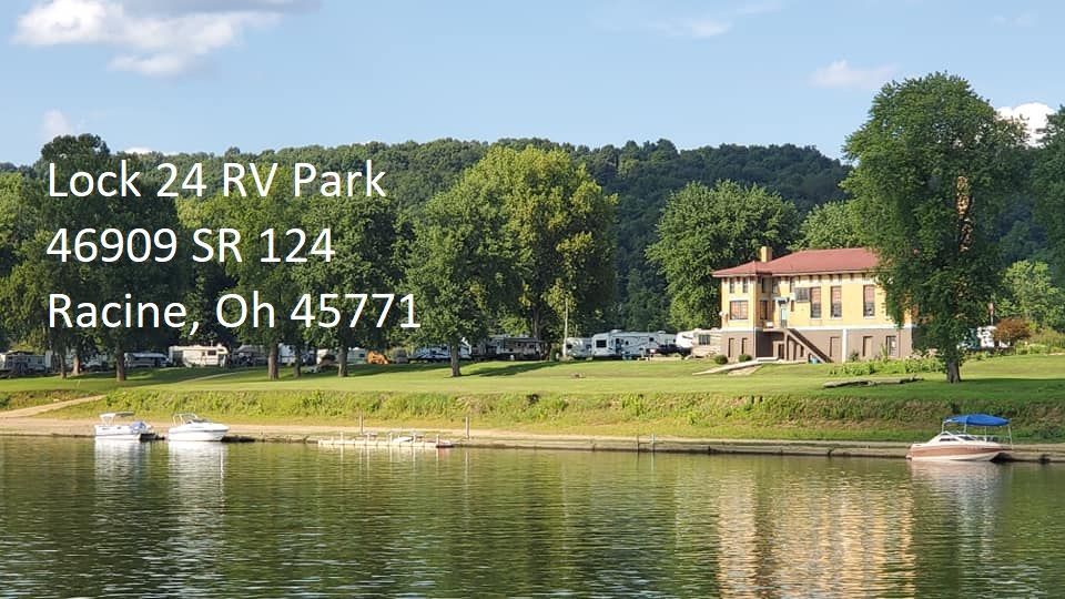 Lock 24 RV Park in Racine, Ohio, with RVs parked on a grassy riverfront lawn beside a historic building.