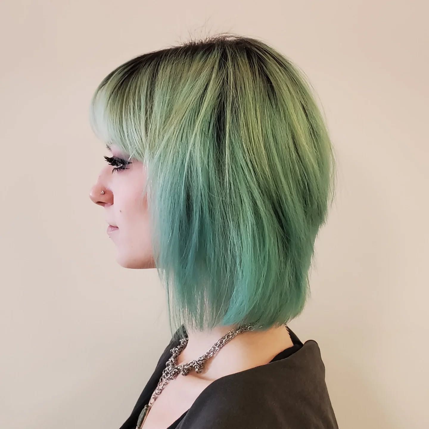 A woman with green hair is wearing a necklace