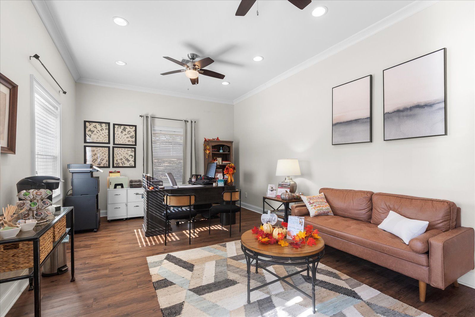 Bright living room with a sofa, dining table, coffee table, and wall art under ceiling fans