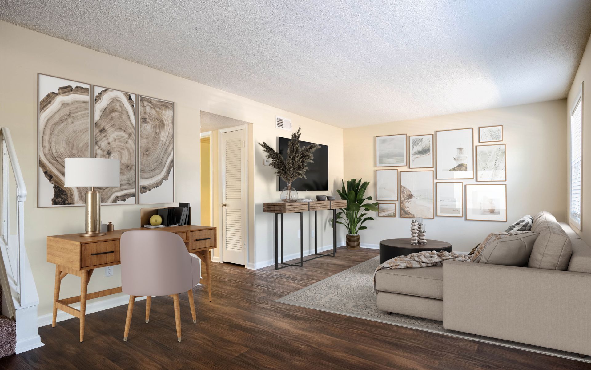 Bright living room with beige sofa, wooden desk, TV, floor lamp, and framed wall art.